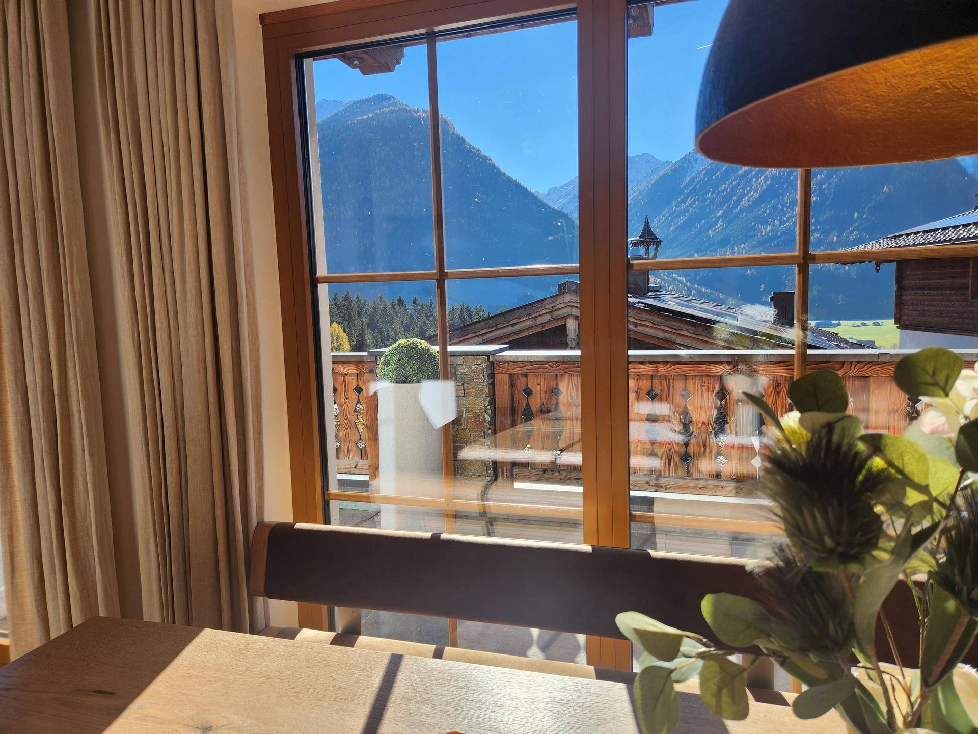 Essbereich mit Bergblick durch große Fenster und traditionellem Holzbalkon.