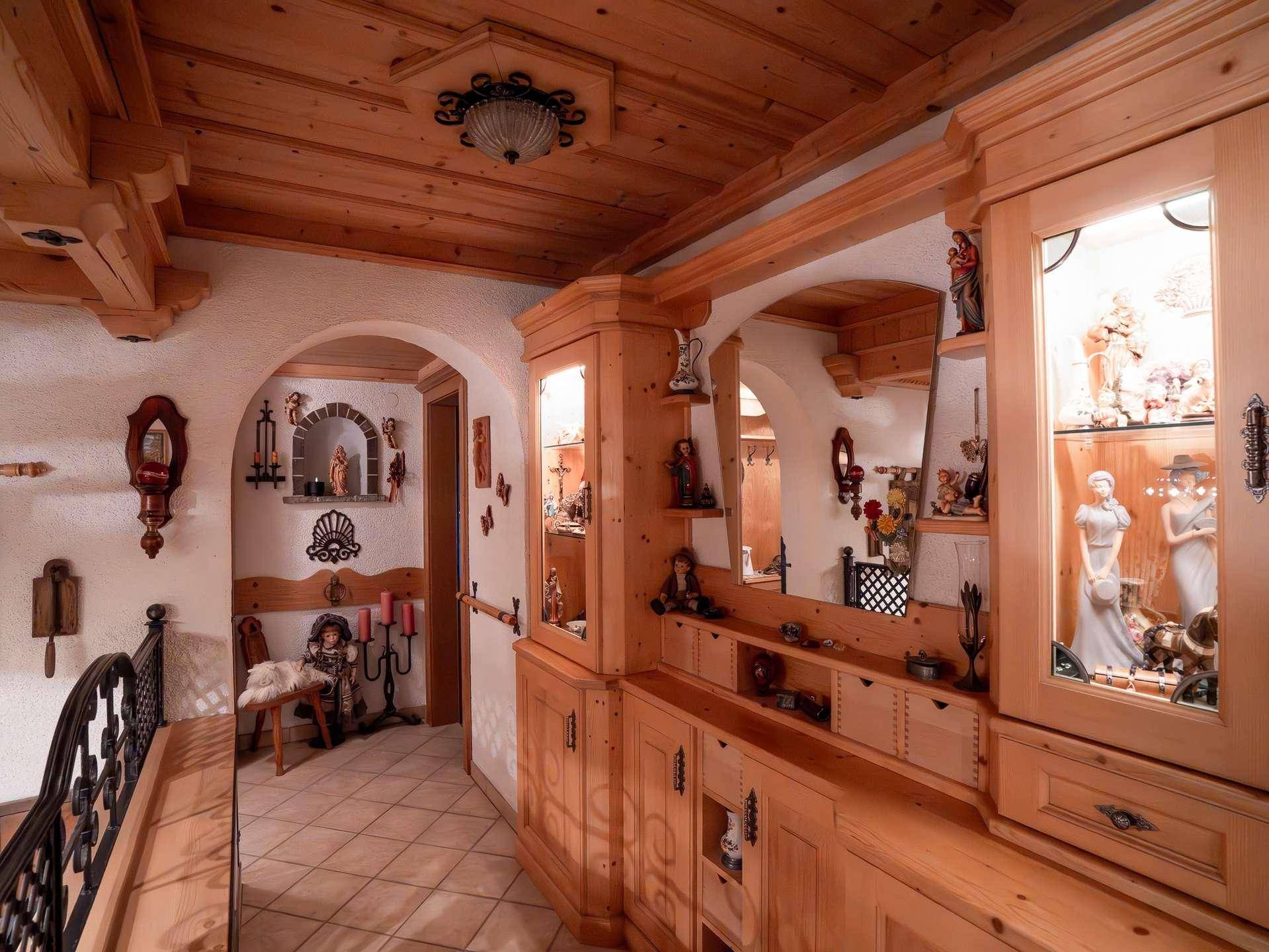 Geräumiger Flur mit Holzvertäfelung, Vitrinen und traditionellen Dekorationen.
