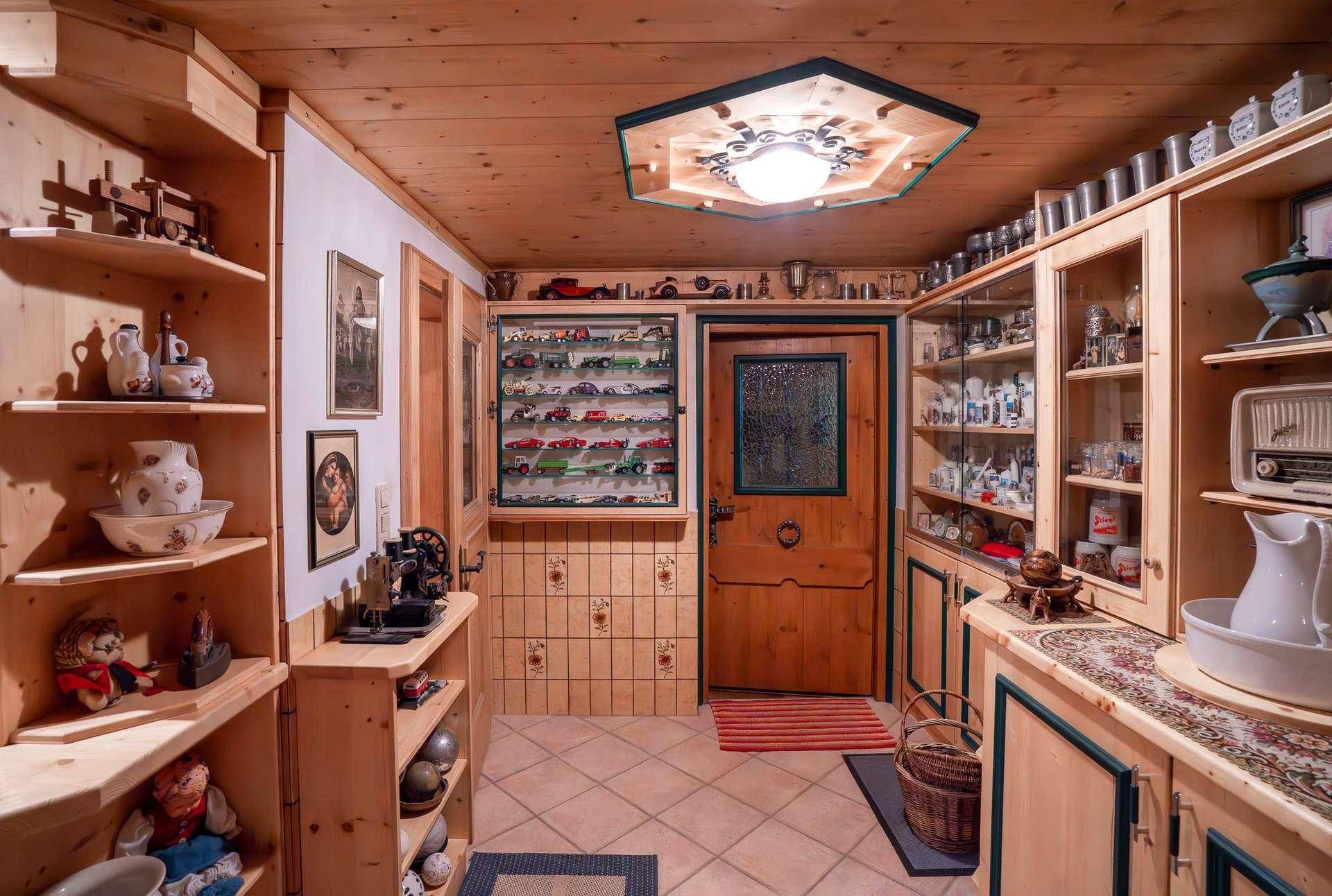 Traditioneller Flur mit Holzvertäfelung, Vitrinen und Fliesenboden.