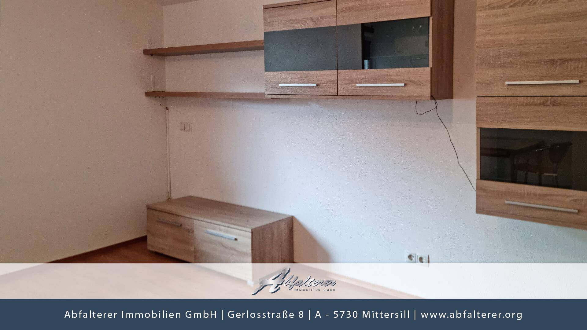 Wohnzimmer mit modernem Holzmobiliar und Regalen an der Wand.