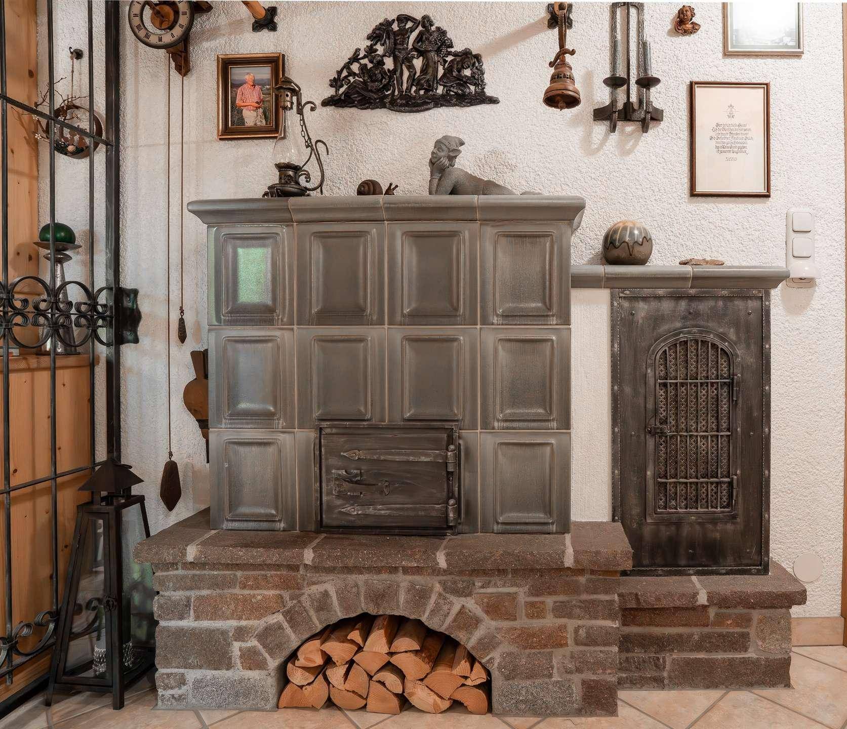 Detailansicht eines traditionellen Kachelofens mit Holzscheiten und rustikaler Dekoration.