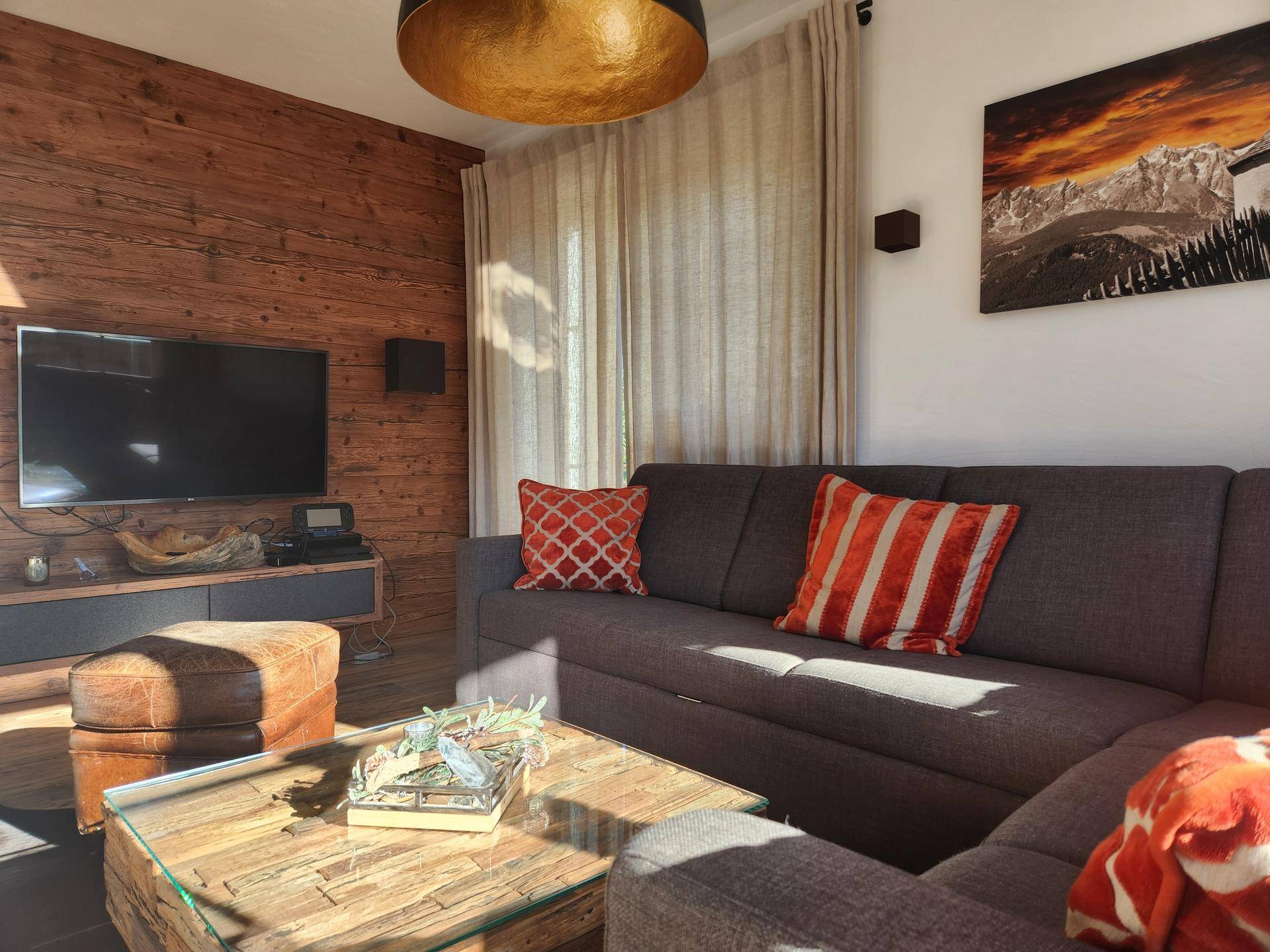 Gemütliches Wohnzimmer mit Holzwand, großem Sofa, modernem Dekor und integriertem Kamin.