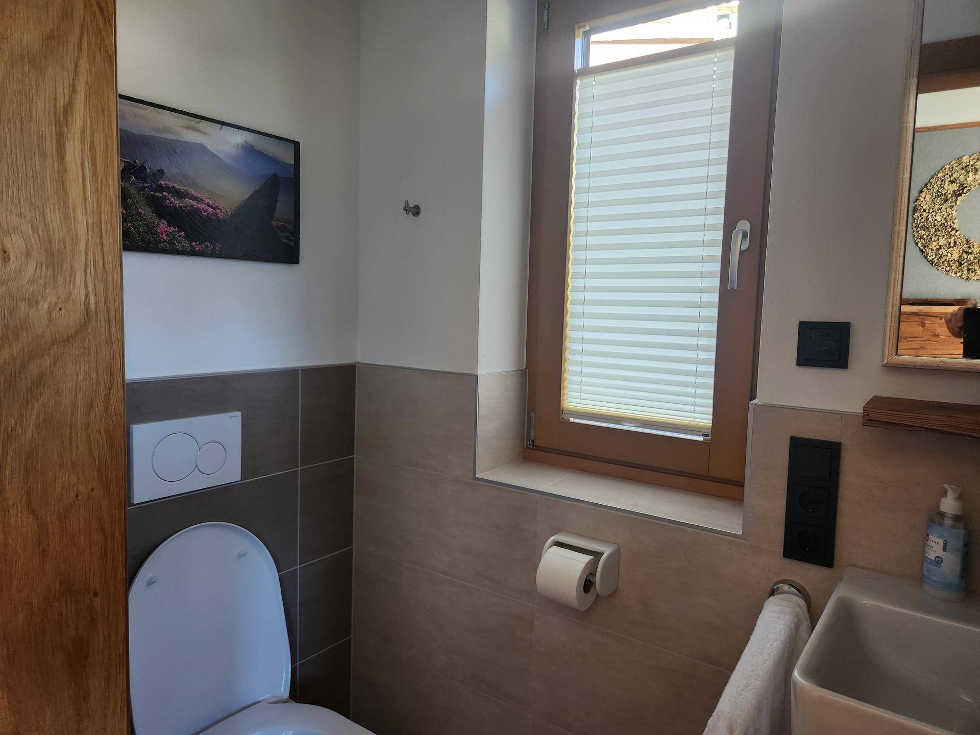 Modernes Gäste-WC mit Wand-WC, kleinem Waschbecken und Fenster.