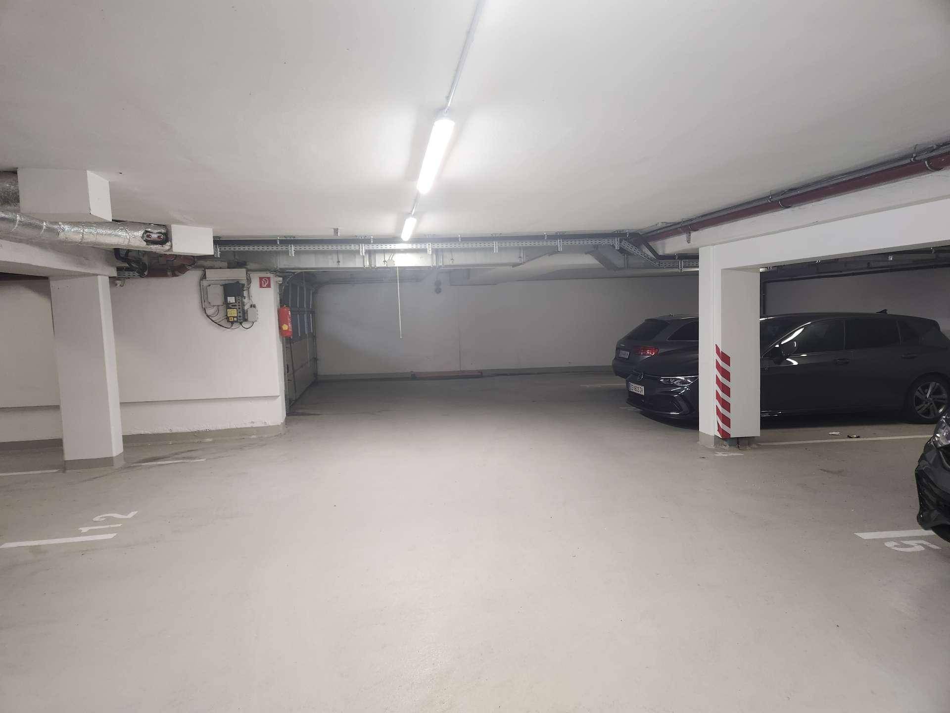 Geräumige Tiefgarage mit mehreren Stellplätzen und guter Beleuchtung, ideal für Bewohner.