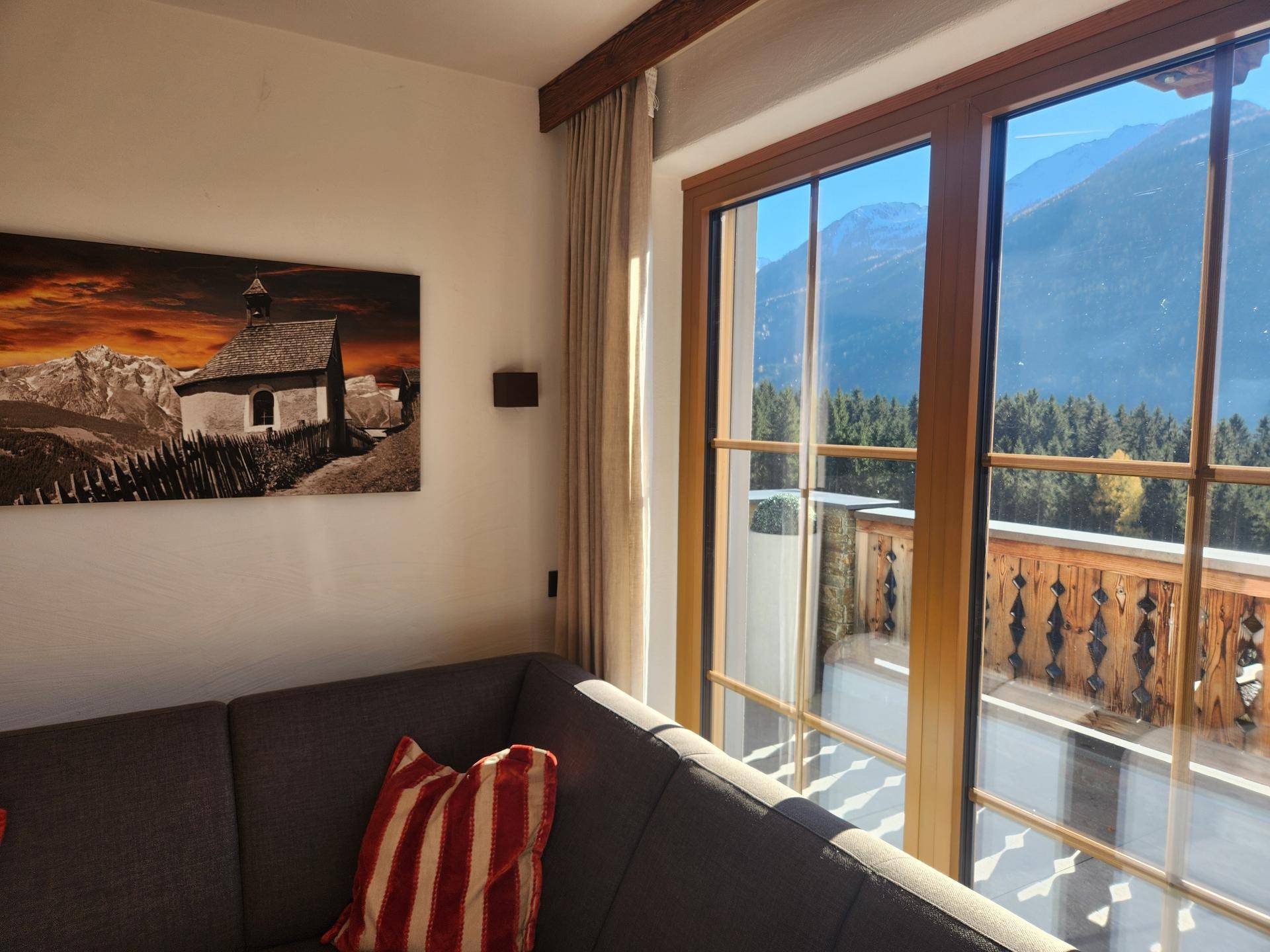 Helles Wohnzimmer mit großen Fenstern und Panoramablick auf die Berge und Wälder.