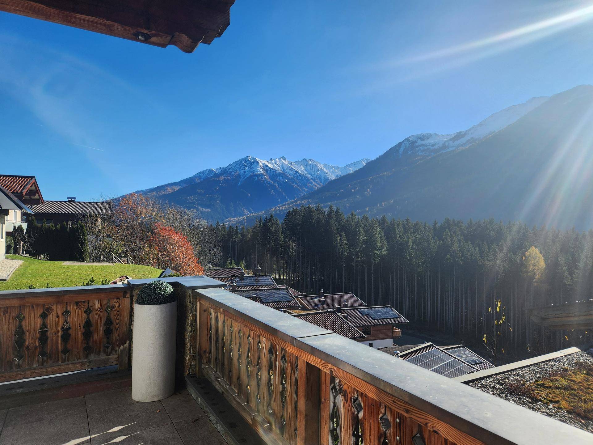Sonniger Balkon mit traditionellem Holzbalkongeländer und atemberaubendem Bergblick.
