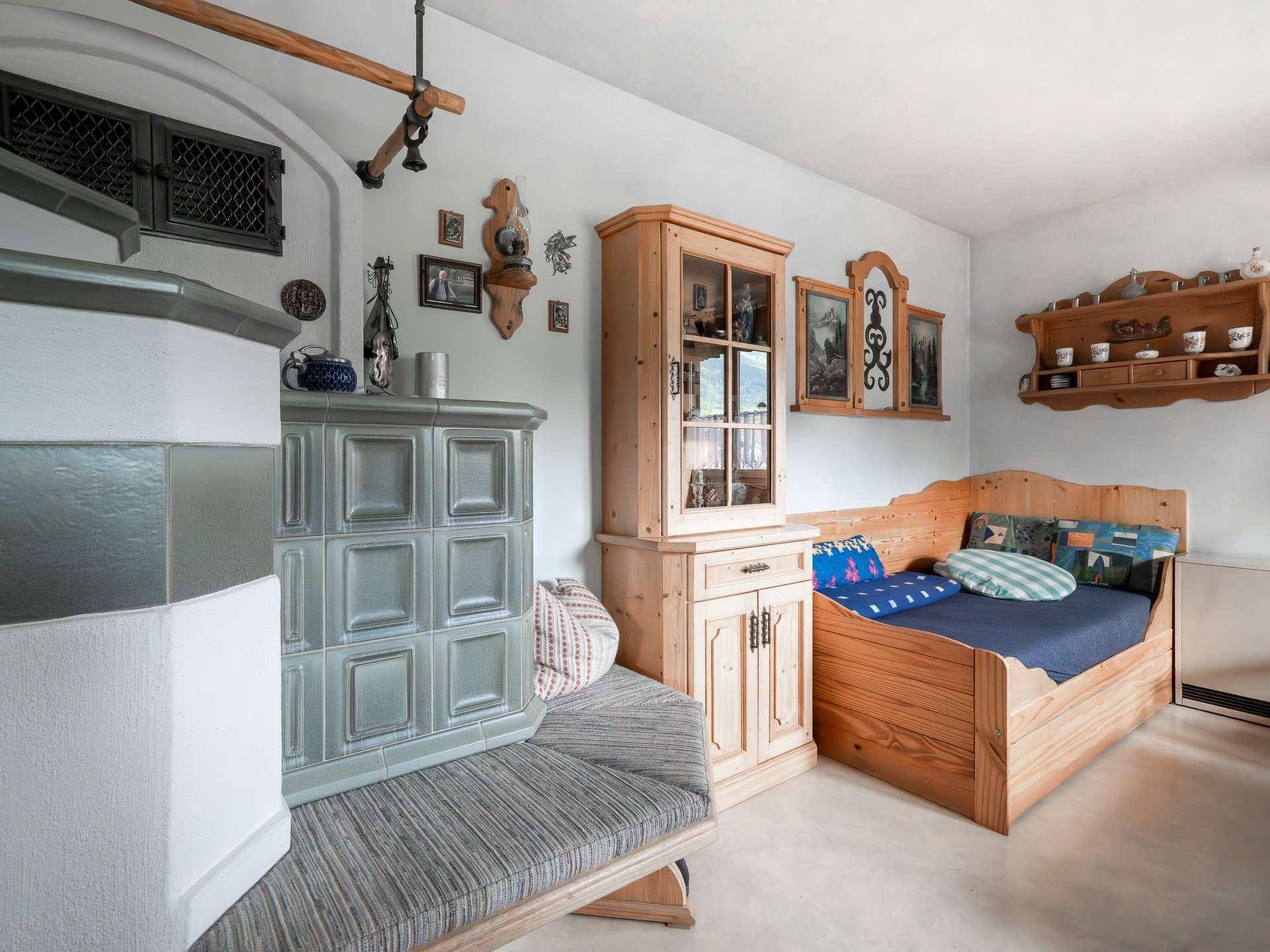 Helles Schlafzimmer mit Kachelofen, Holzmöbeln und traditioneller Dekoration.