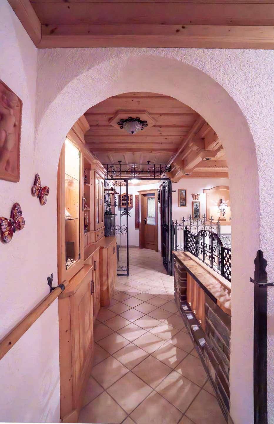 Heller Flur mit Rundbogen, Holzdecke und traditionellen Dekorationen.