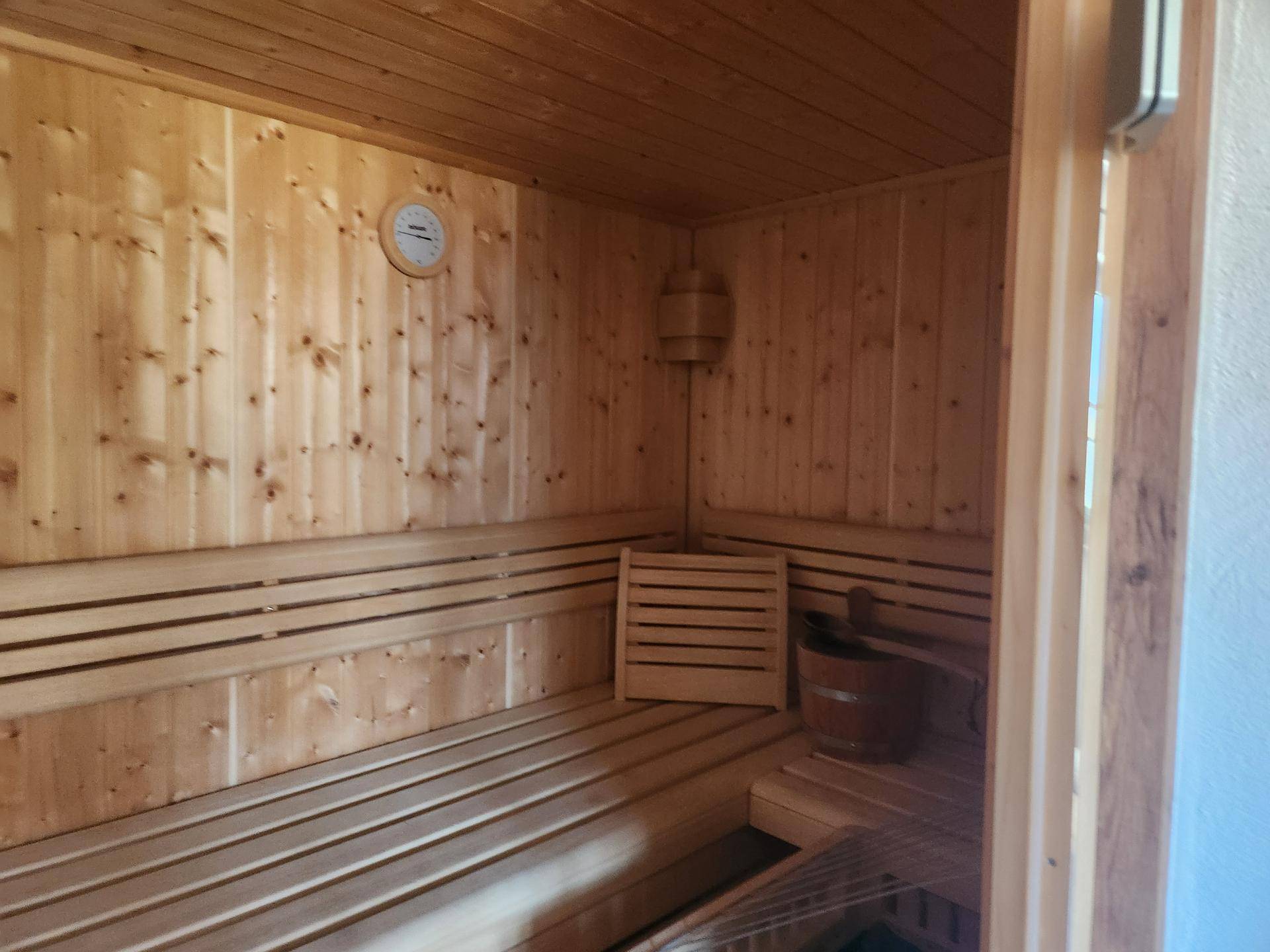 Traditionelle Holzsauna mit Bänken und Saunaofen für entspannende Momente.