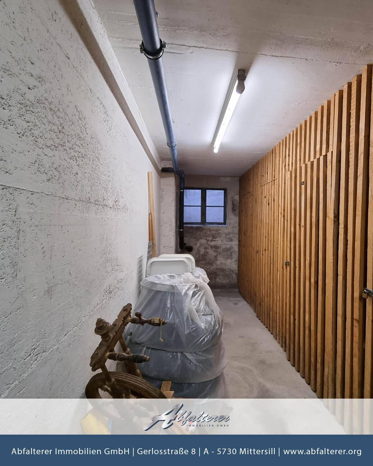 Kellerraum mit Betonwänden, Holzverkleidung und sichtbaren Rohren, ideal als Abstellfläche.