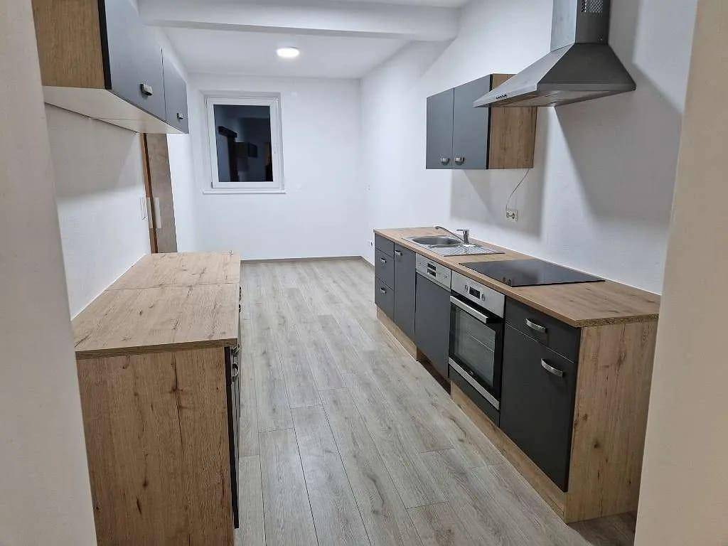 Neue Küche mit Holz- und Anthrazitfronten, integriertem Geschirrspüler und Dunstabzugshaube.