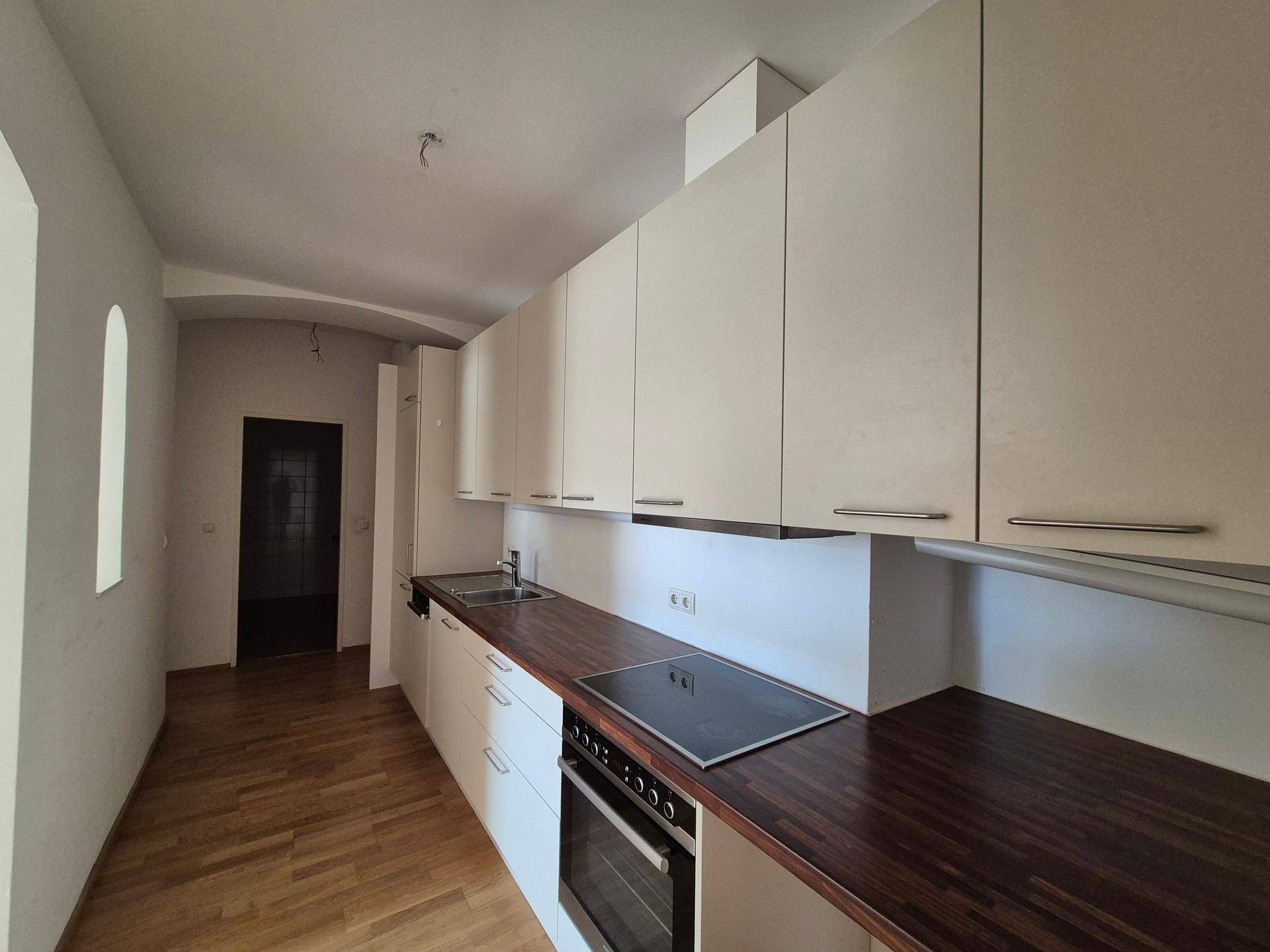 Moderne Küche mit weißen Hängeschränken, dunkler Arbeitsplatte und integrierten Geräten.