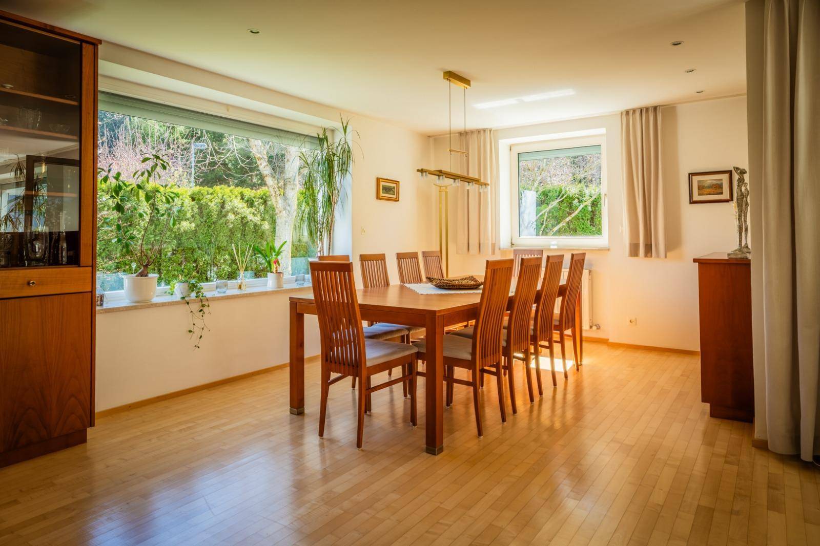 Geräumiger Essbereich mit Holztisch und Stühlen, großen Fenstern und hellem Parkettboden.
