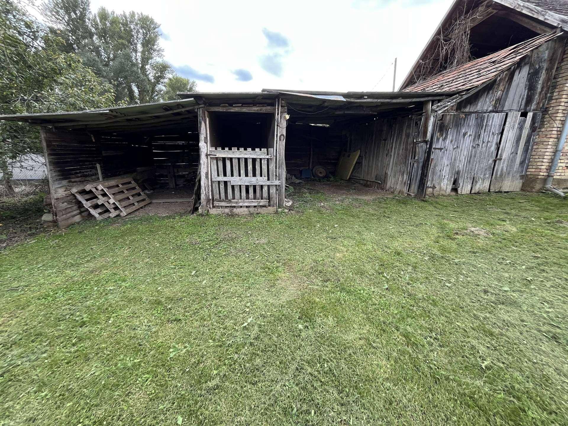Nahaufnahme eines verfallenen Holzschuppens oder einer Scheune auf einem ländlichen Grundstück mit Grasfläche.