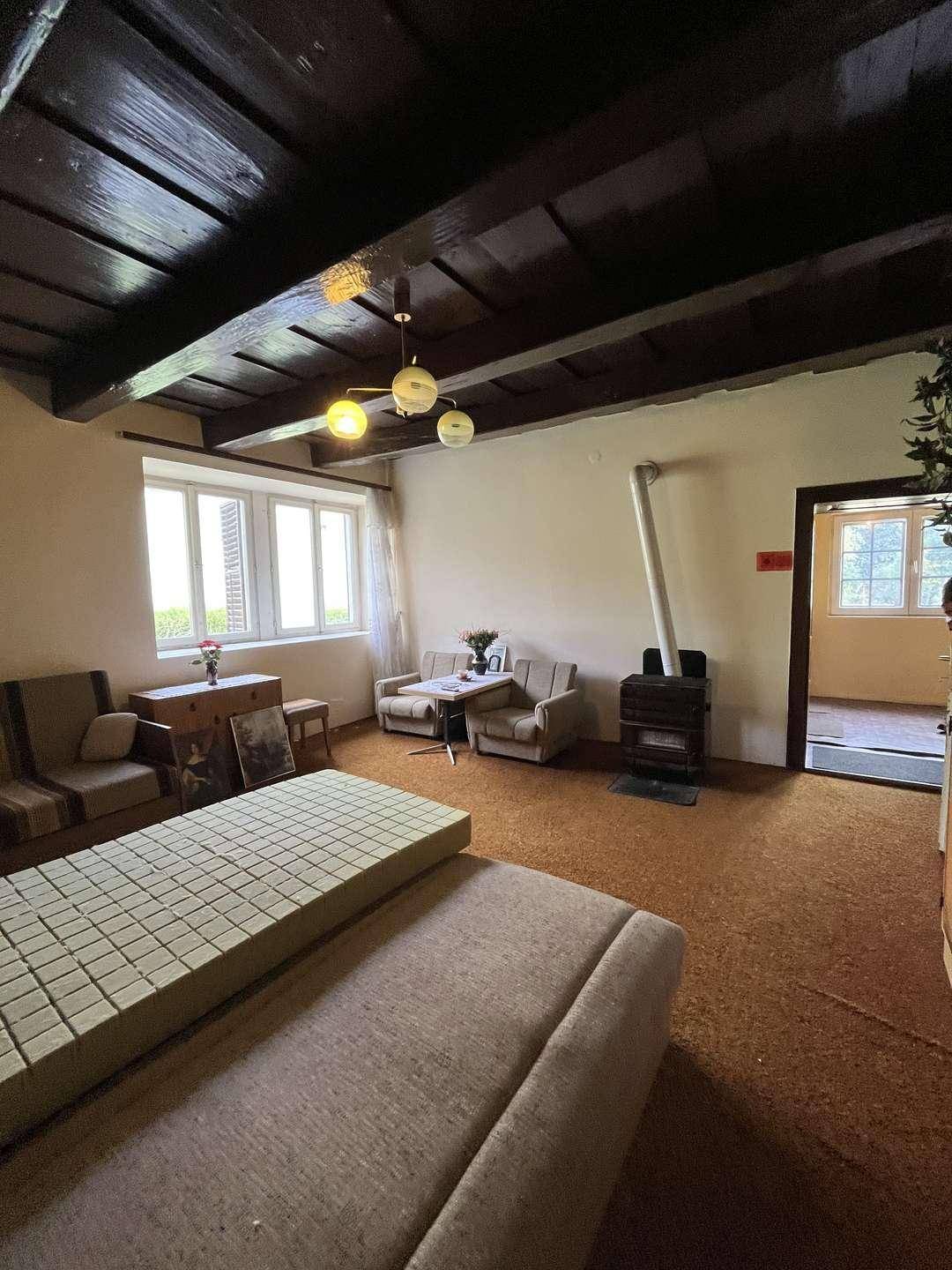 Gemütliches Wohnzimmer mit traditionellen Möbeln, Holzbalken und Kaminofen.