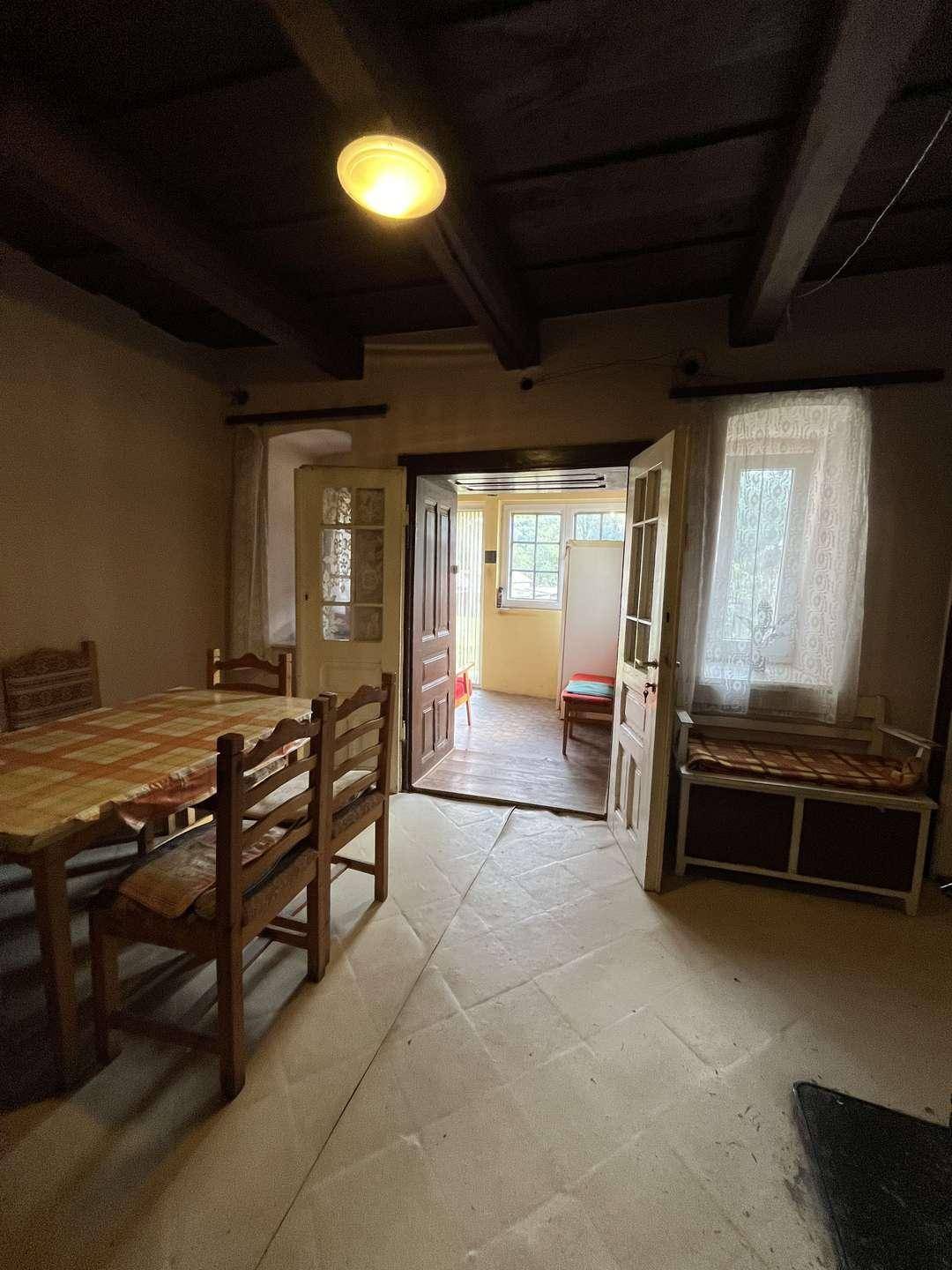 Esszimmer mit Holztisch und Stühlen, Fenster und Durchgang zu weiteren Räumen.