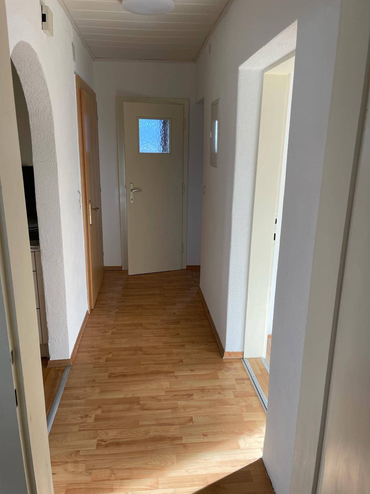 Heller Flur mit Laminatboden, weißen Wänden und Holztäfelung an der Decke.