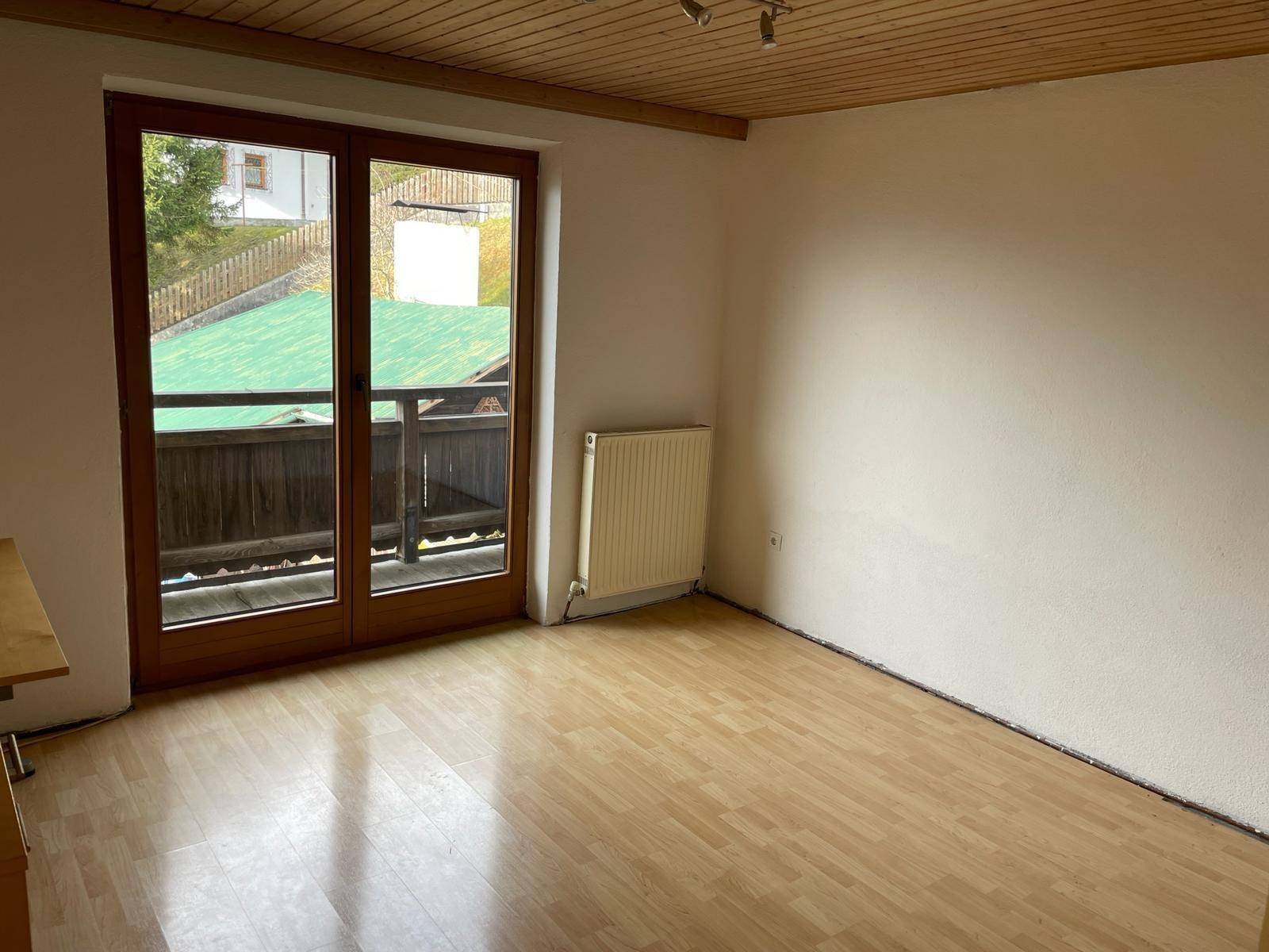 Geräumiges Zimmer mit Laminatboden und Zugang zu einem Balkon oder einer Terrasse.