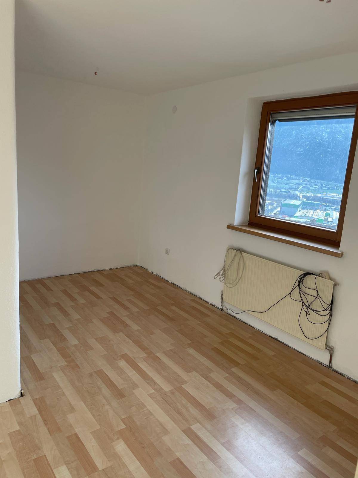 Geräumiges Schlafzimmer mit Laminatboden und weitem Blick auf die umliegende Berglandschaft.