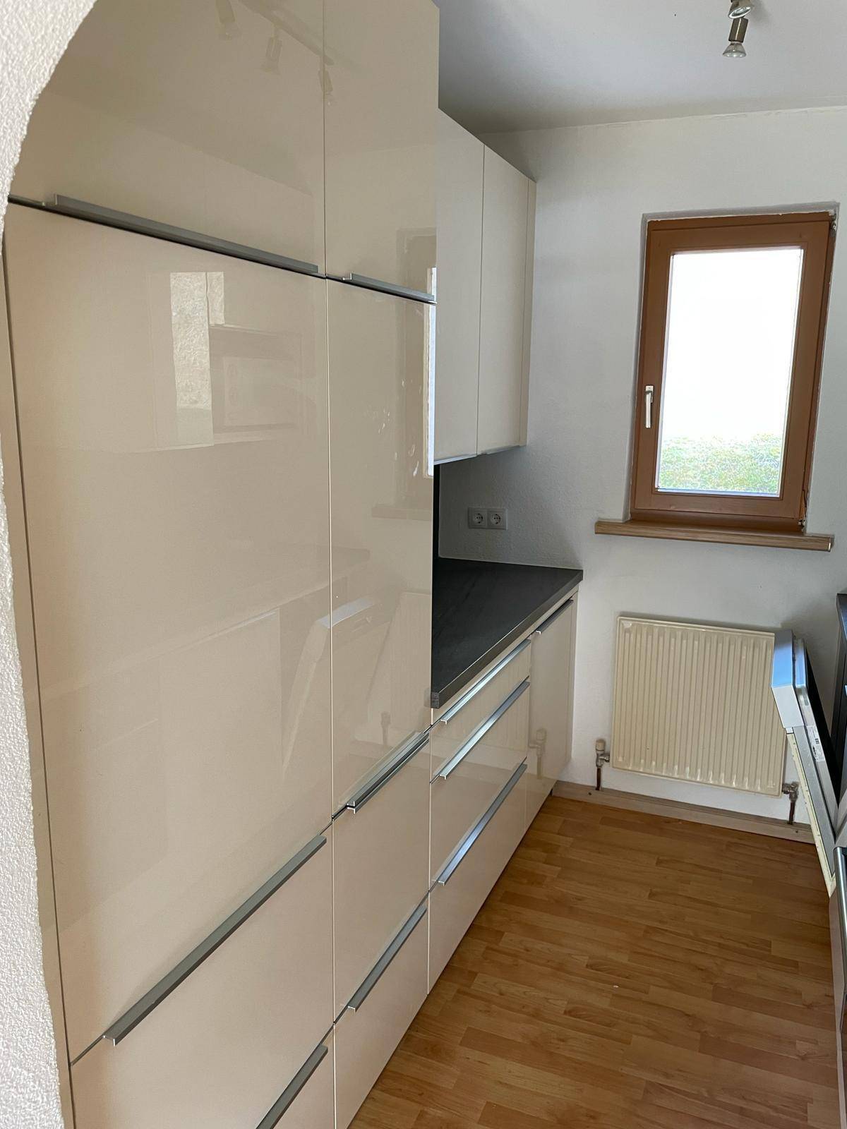 Moderne Küche mit hohen, glänzenden Schränken und integrierten Geräten.