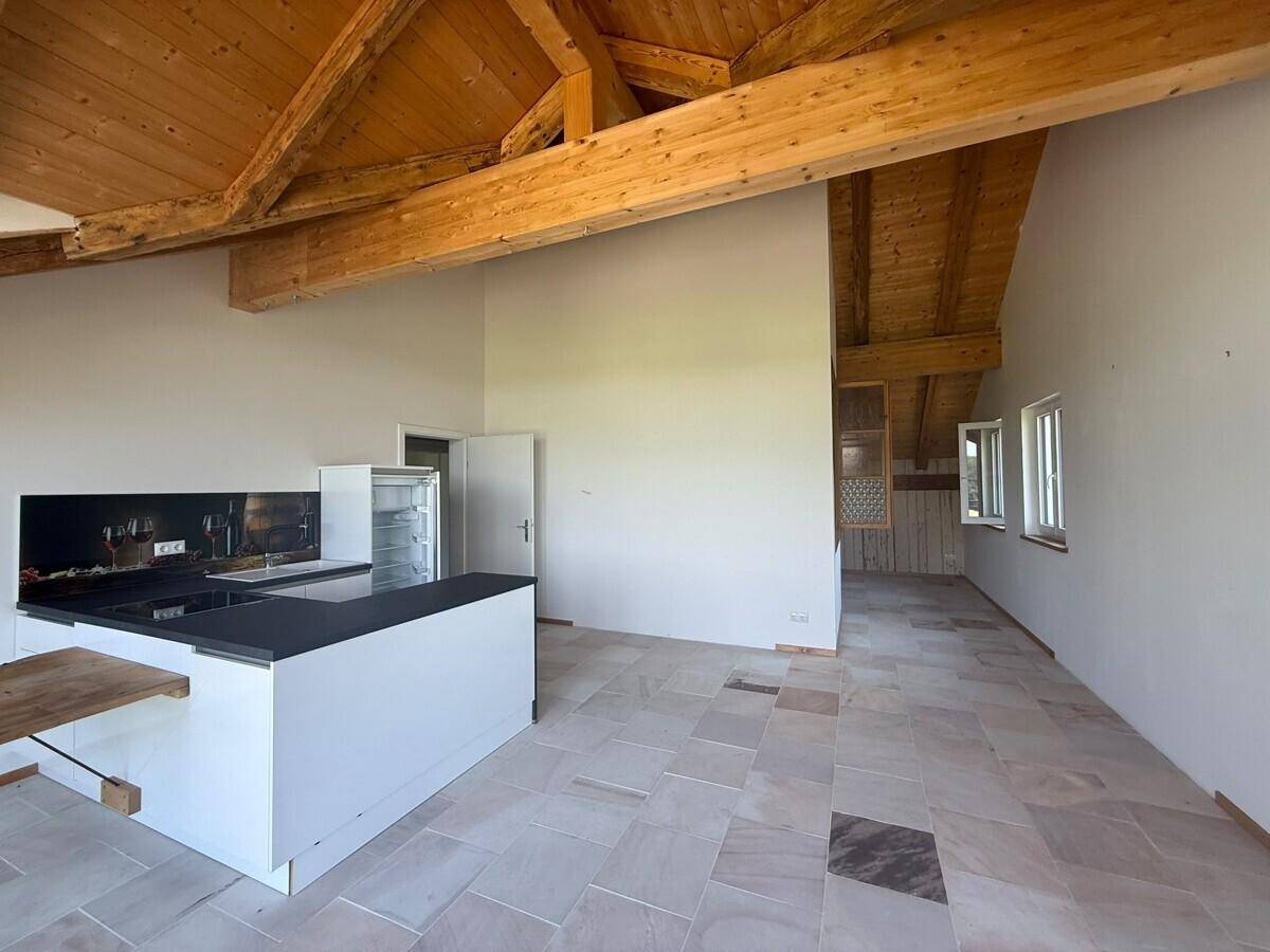 Offene Küche mit moderner Kücheninsel, Holzbalkendecke und Schieferboden.