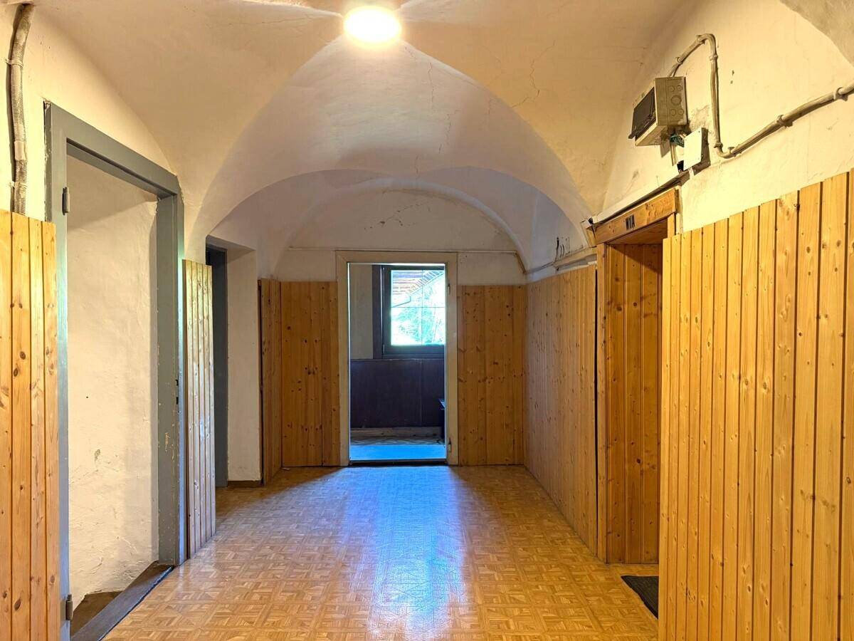 Flur mit Gewölbedecke und Holzvertäfelung an den Wänden, der zu weiteren Räumen führt.
