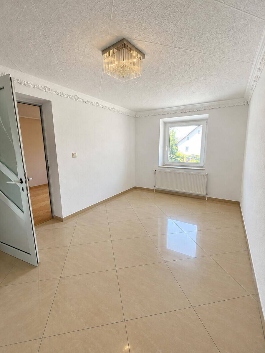 Heller Raum mit glänzenden Fliesen, weiß gestrichenen Wänden und einem Fenster.