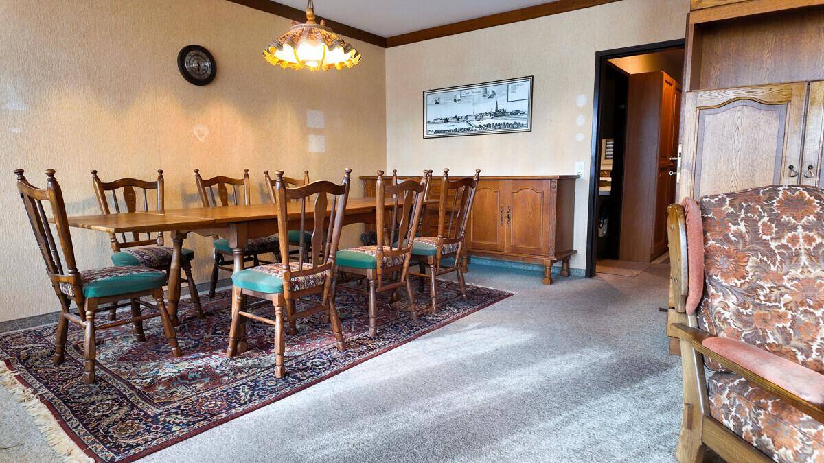 Traditioneller Essbereich mit großem Holztisch, passenden Stühlen und einem gemusterten Teppich.