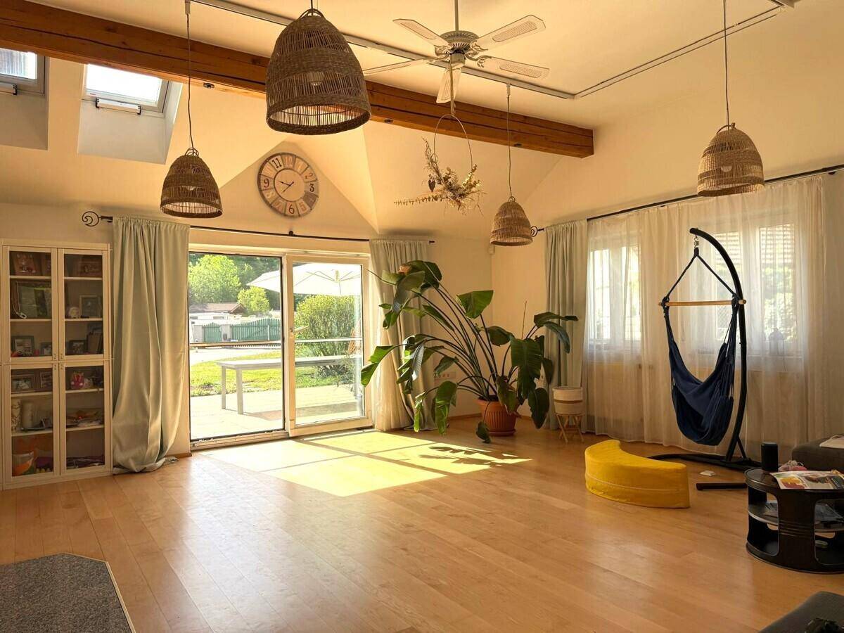 Helles Wohnzimmer mit hohen Decken, Holzbalken und Zugang zur Terrasse.