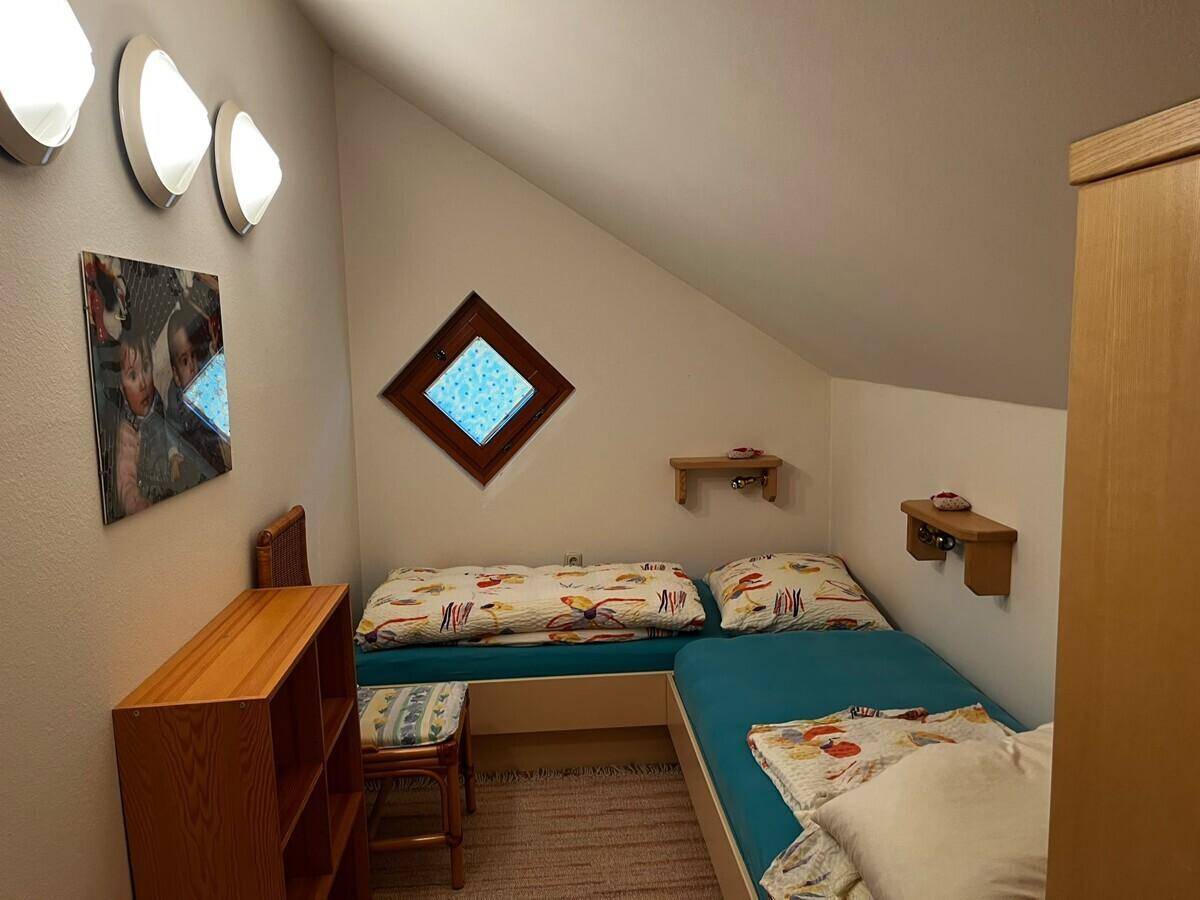 Helles Dachgeschosszimmer mit zwei Einzelbetten und schräger Decke.
