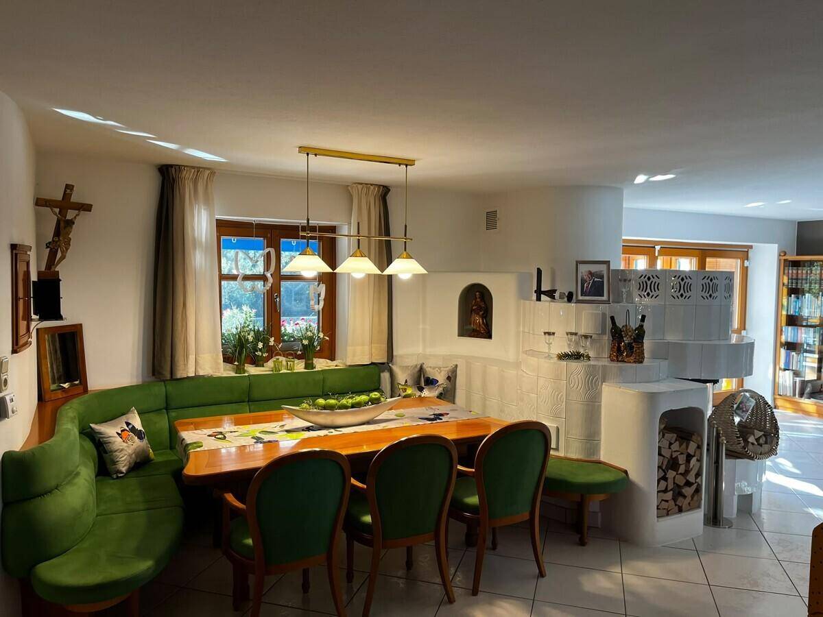Traditioneller Essbereich mit Eckbank, Holztisch und dekorativem Kachelofen.