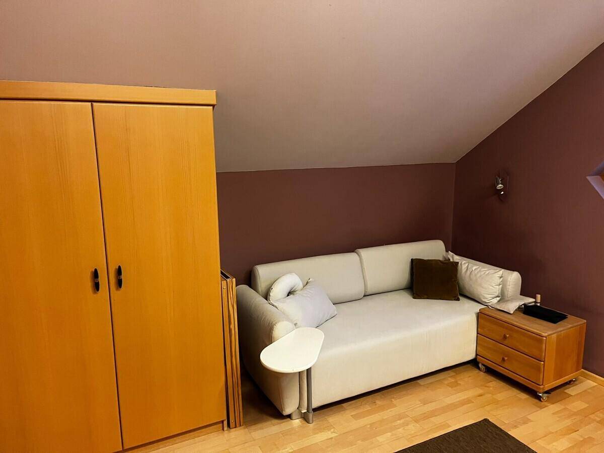 Dachgeschosszimmer mit Schlafsofa, Holzschrank und schräger Decke.