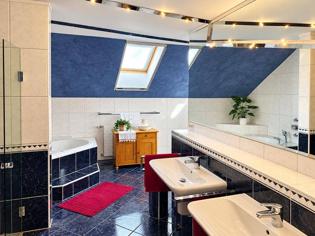 Geräumiges Badezimmer mit Doppelwaschbecken, Badewanne und Dachfenster.