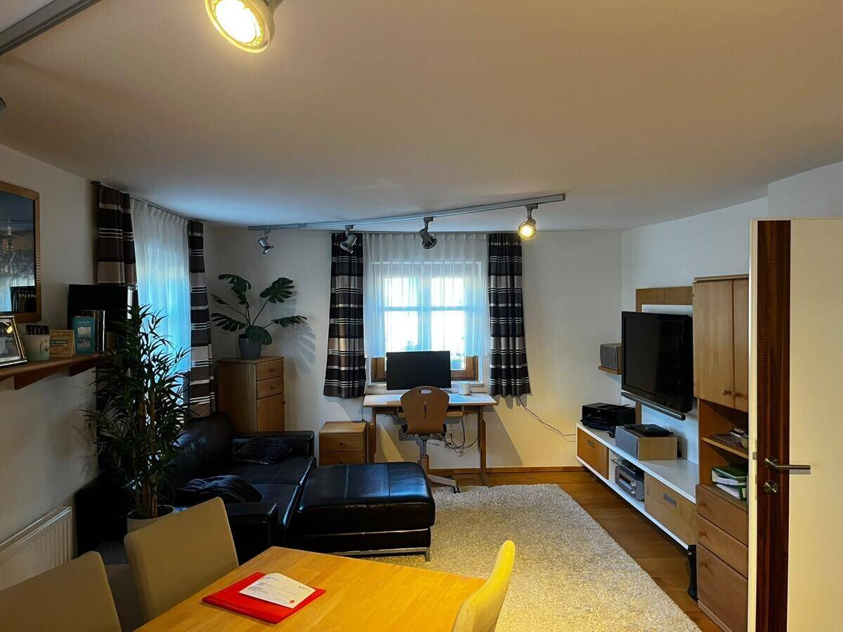 Helles Wohnzimmer mit Schreibtisch, Teppichboden und Blick ins Grüne.