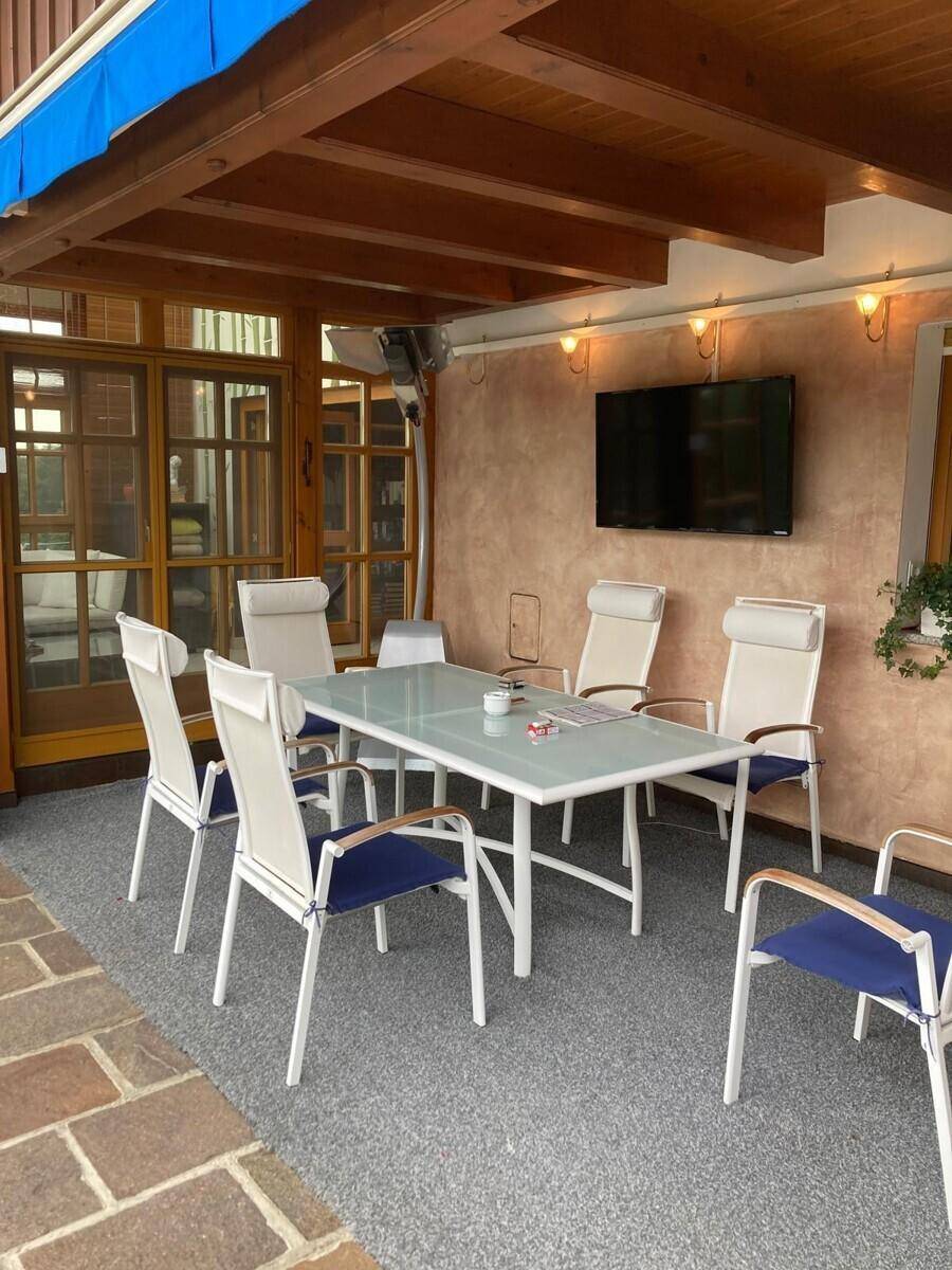 Überdachte Terrasse mit Esstisch, Stühlen und Außenfernseher für gesellige Stunden.