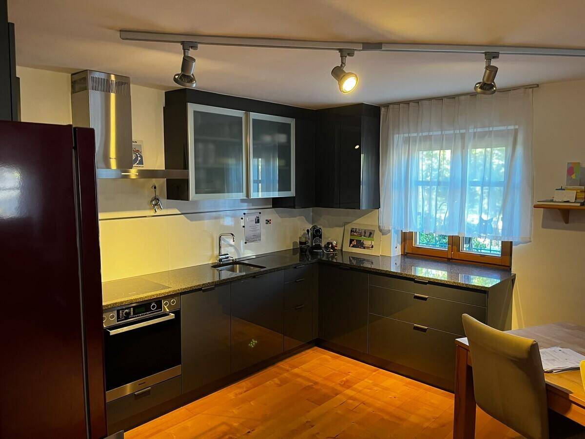 Dunkle Küche mit Holzfußboden, modernen Geräten und Fenster mit Vorhängen.