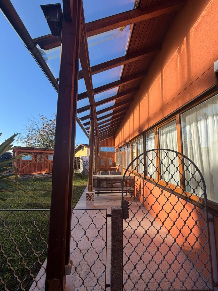 Überdachte Terrasse mit Holzbalken und Blick auf den Garten an einem sonnigen Tag.
