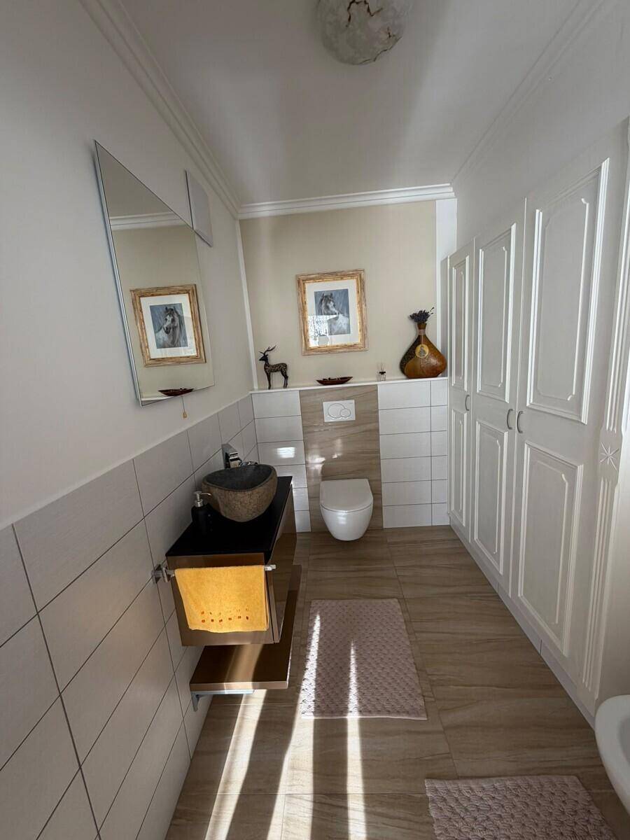 Elegantes Gäste-WC mit modernem Waschbecken, Wand-WC und Einbauschränken.