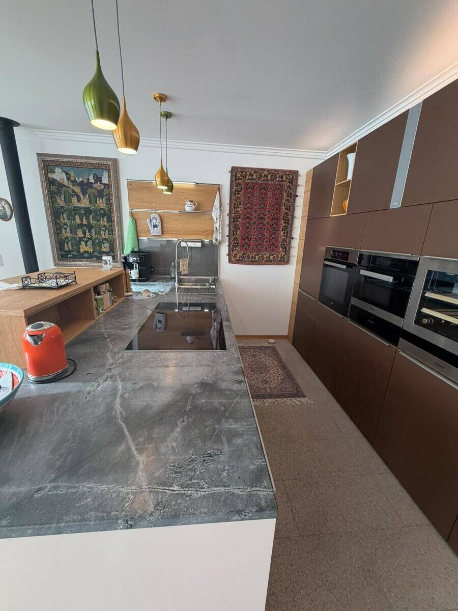 Moderne Küche mit dunklen Schränken, Kücheninsel und integrierten Geräten.