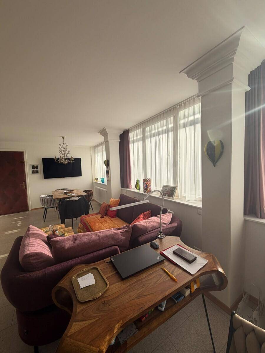Helles Wohnzimmer mit bequemen Sofas, einem Holztisch und großen Fenstern.
