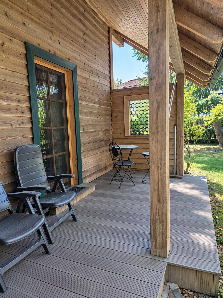 Überdachte Holzterrasse mit Sitzgelegenheiten und Blick ins Grüne, ideal für entspannte Stunden im Freien.