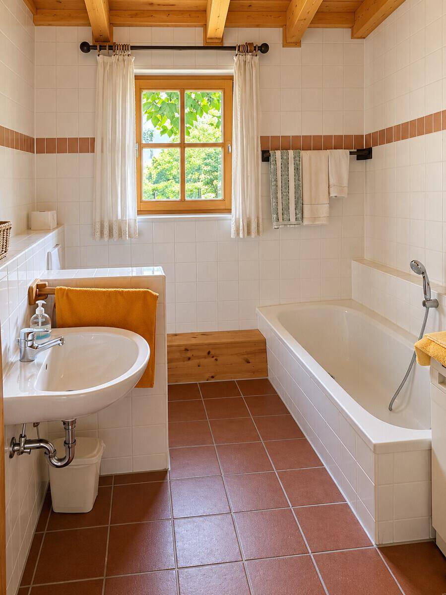 Helles Badezimmer mit Badewanne, Fenster und rustikalen Holzdetails, ausgestattet mit Fliesenboden.