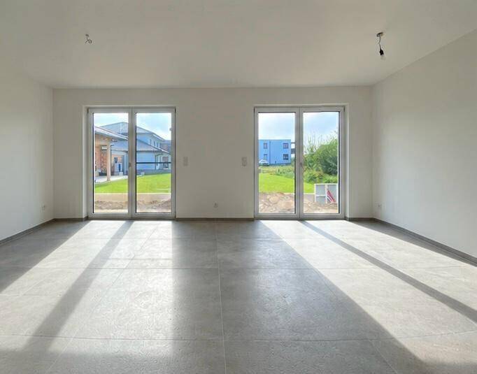 Lichtdurchfluteter Wohnbereich mit großen Glastüren und Blick ins Grüne.