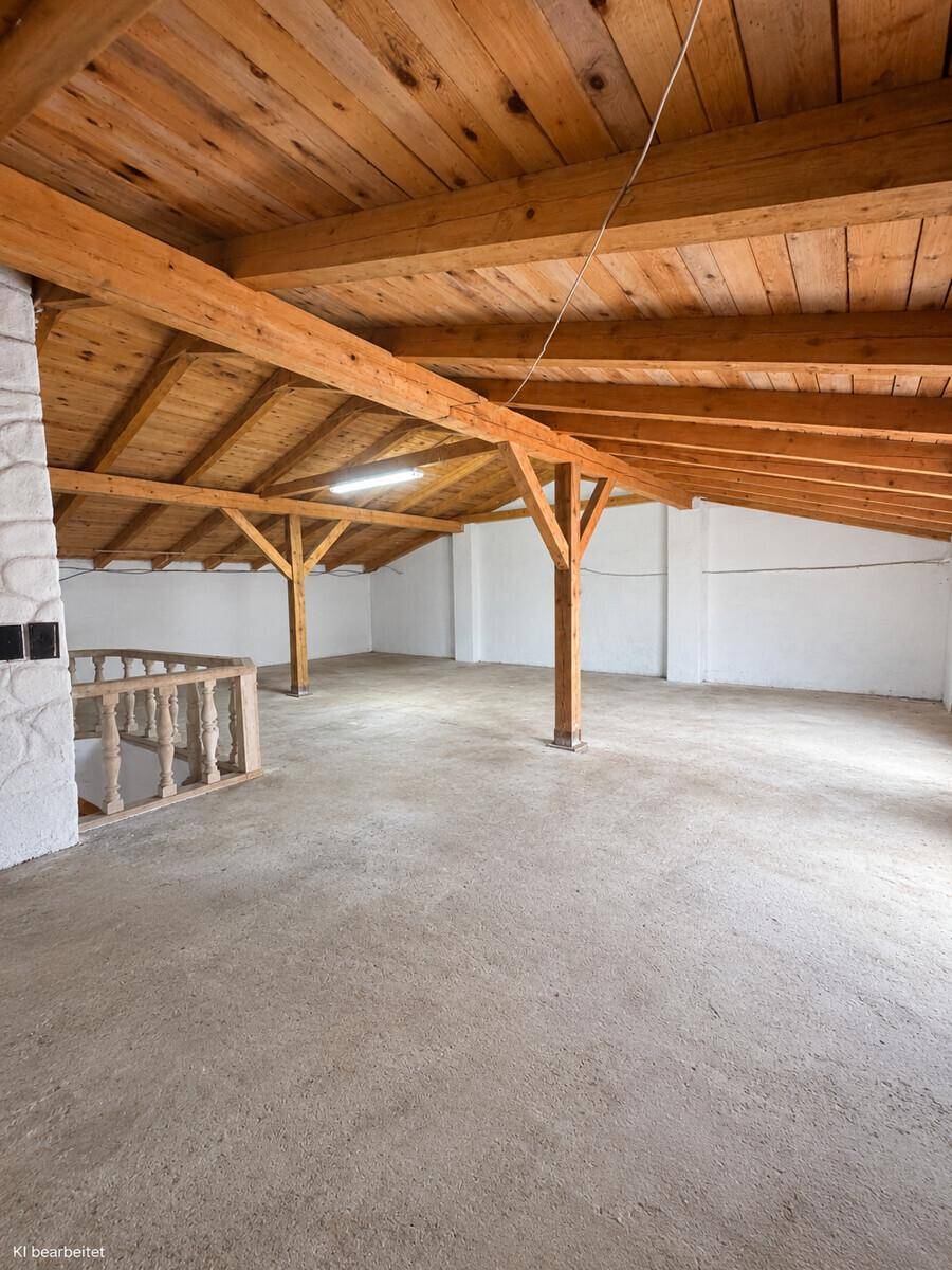Geräumiger Dachboden mit sichtbaren Holzbalken und Holzdecke, bereit für den Ausbau.
