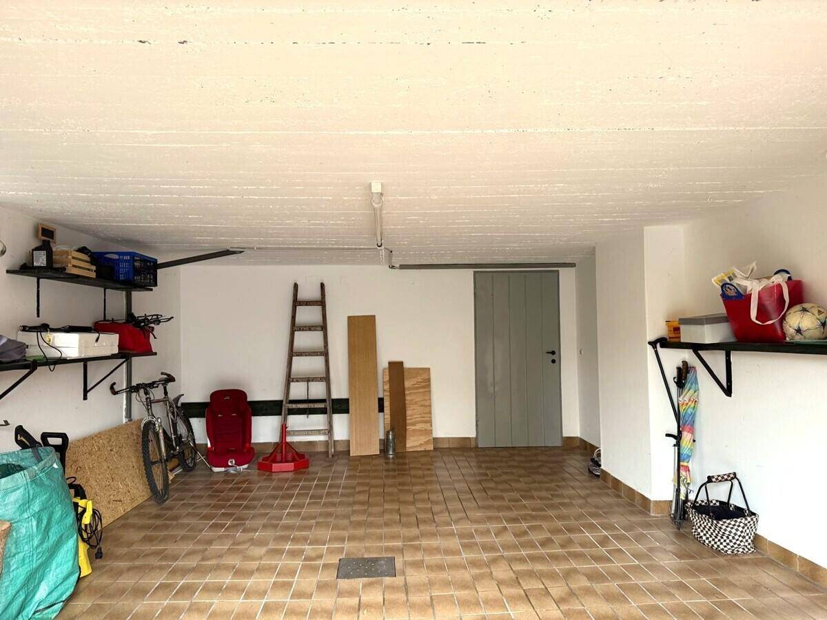 Geräumige Garage mit Fliesenboden, Regalen und Stauraum für Fahrräder.