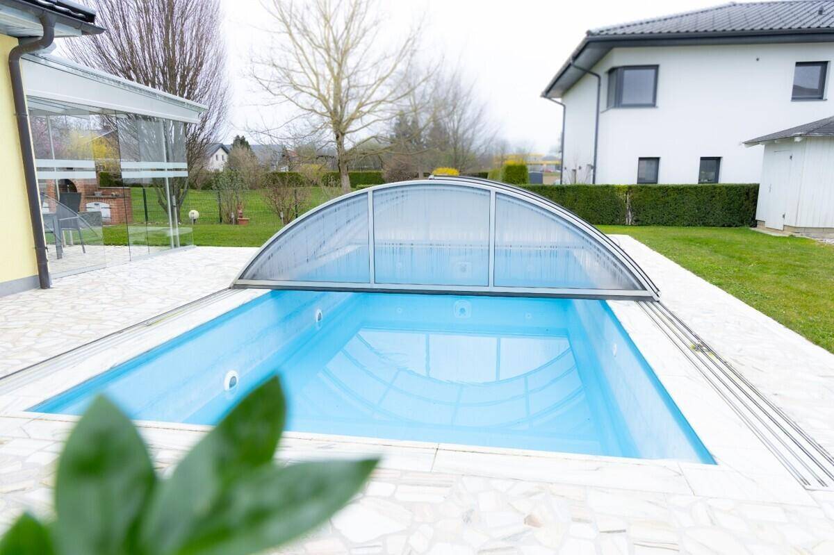 Außenpool mit transparenter Überdachung im gepflegten Gartenbereich des Anwesens.