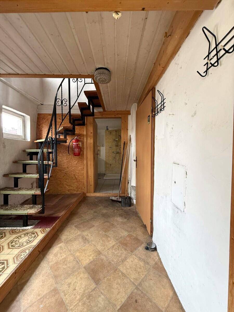 Flur mit rustikalen Holzdecken, gemusterten Fliesen und einer schmiedeeisernen Treppe zum Obergeschoss.