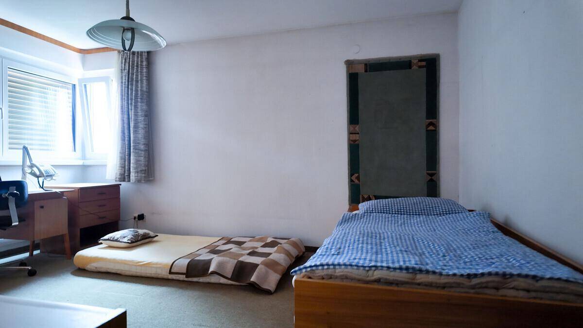Schlafzimmer mit zwei Betten, einem Schreibtisch und einem Fenster für natürliches Licht.