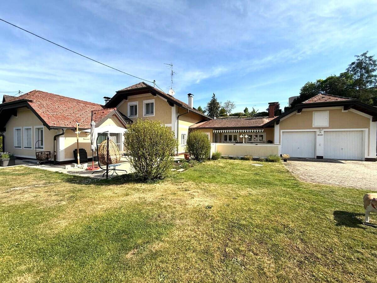 Großzügiger Gartenbereich mit weitläufiger Rasenfläche, Hausfassade und einer praktischen Doppelgarage.
