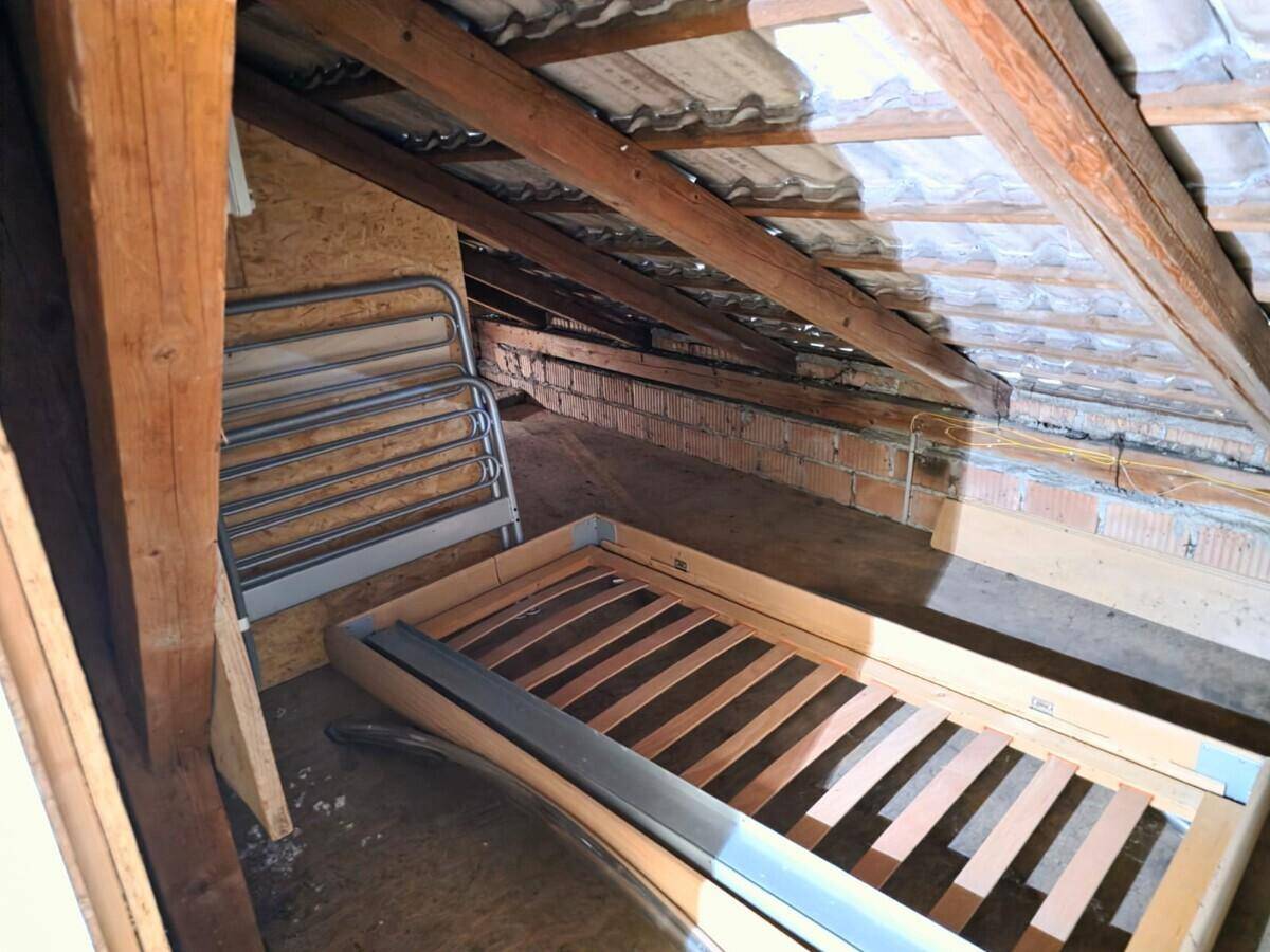 Unausgebauter Dachboden mit sichtbaren Holzbalken und Dachkonstruktion, genutzt als Lagerraum.
